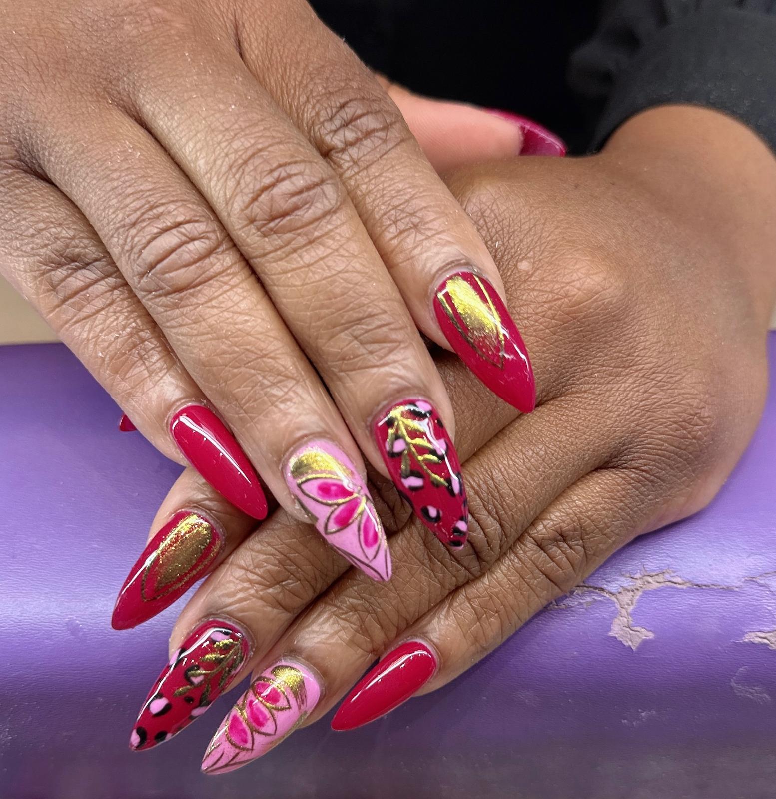 Rode nagels met goudkleurige en roze nageldecoratie
